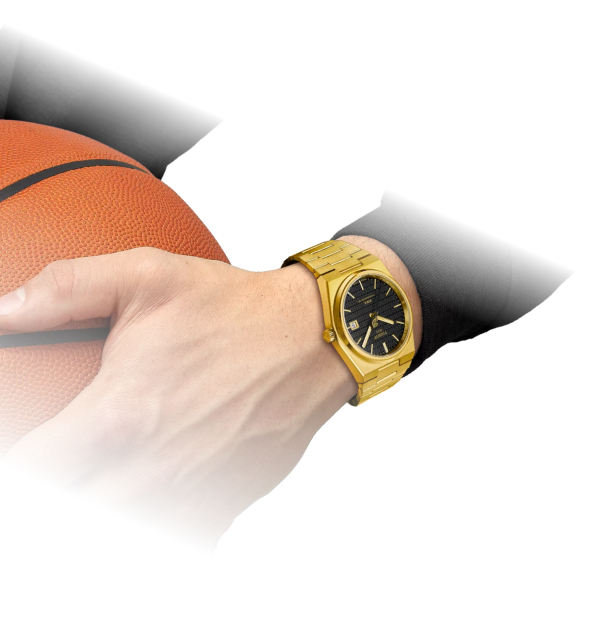 Close-up of a hand gripping an orange basketball, wearing a gold wristwatch and a black sleeve."